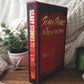 Book titled 'Scary Stories to Tell in the Dark' on a surface with a plant and candle in the background.